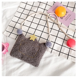 Detail of grey plush crown kids bag with purple pom-pom on checkered background