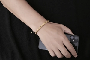Detailed view of a golden stainless steel wheat chain bracelet on a model wrist