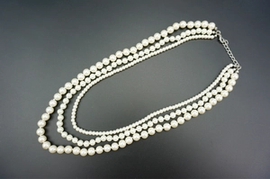 Detail of three-layer glass pearl necklace showing silver lobster clasp and extender