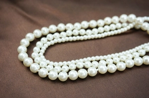 Macro shot of multi-layer white pearl necklace strands on a dark silk background