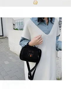 Detail of black lamb fleece crossbody bag with brown bear embroidery on a street model