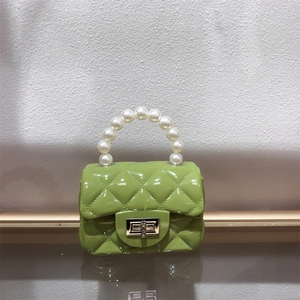 Detail of green mini jelly bag featuring pearl handle, metal lock, and quilted texture