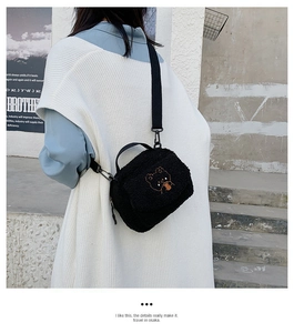 Detail of black faux shearling bag with cartoon bear embroidery and adjustable strap