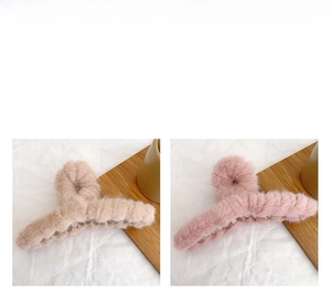 Detailed close-up of khaki and pink fuzzy plush claw clips on a white fabric surface