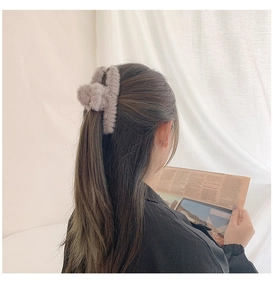 Close-up of a dusty pink plush shark hair claw clip on a woman's bun hairstyle