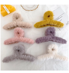 Flat lay of six large faux fur claw clips in various pastel colors on soft white fabric