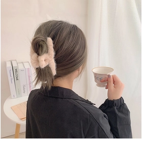 Detail showing soft plush hair claw clip in beige on model with cozy aesthetic