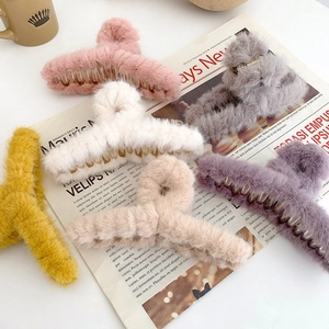 Soft faux fur hair claw clips in five pastel colors on a vintage newspaper background