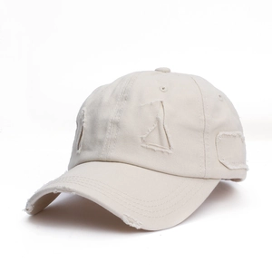 Close-up of cream distressed baseball cap showing frayed holes and vintage cotton texture