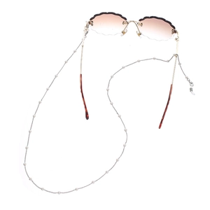 Macro detail of cloud-shaped rimless sunglasses with gold frame and pearl chain