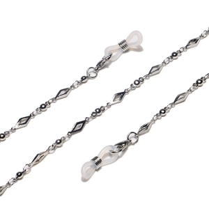 Chaîne de lunettes argentée avec maillons losanges évidés et perles en métal sur fond blanc