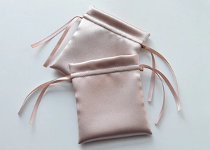 Close-up of champagne satin drawstring gift bags for jewelry with silky texture detail