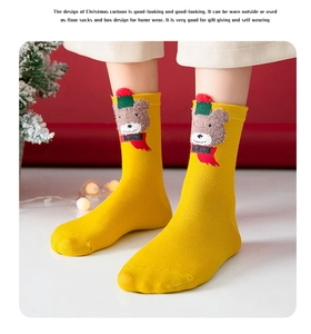 Detail view of a yellow Christmas sock with a plush cartoon bear wearing a festive scarf