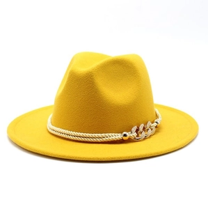 Détail d'un chapeau fedora en laine jaune avec cordelette dorée et gourmette en métal doré