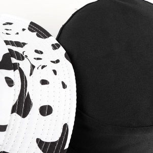 Gros plan des coutures du bob sur toile noire et à motif de vache imprimé