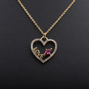 Golden heart necklace with LOVE lettering and red zircon on black leather background