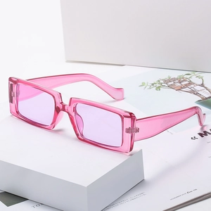 Rosafarbene transparente rechteckige Sonnenbrille auf einem weißen geometrischen Würfel