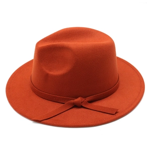 Close-up of rust red wool fedora hat featuring flat brim and matching ribbon band