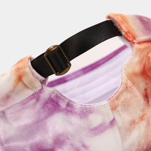 Détail du bonnet tie-dye avec lanière en cuir noir et boucle en métal bronze vintage