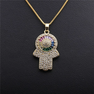 Golden Hamsa Hand necklace with colorful zircon evil eye pendant on black surface