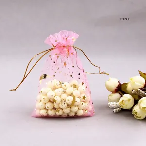 Detail of pink organza drawstring gift bag with gold star and moon patterns and white pearls