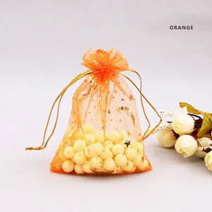 Close-up of orange organza drawstring bag with gold star and moon foil printing