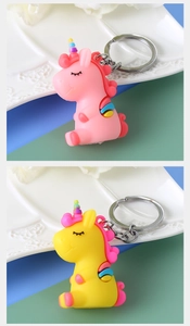 Detail of pink and yellow PVC cartoon unicorn keychains with silver metal rings