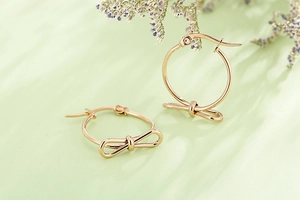 Gros plan détaillé de boucles d'oreilles nœud en or rose au design créole rond pour femme