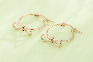 Détail macro de créoles nœuds en or rose avec un design de nœud poli élégant