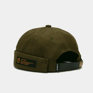 Close-up of olive green docker hat featuring adjustable strap and woven brand label