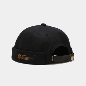 Detail of black cotton Miki hat with orange woven label and adjustable metal buckle strap