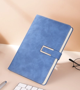 Blue business notebook with textured faux leather cover and a metal buckle on a desk