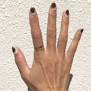 Close-up of dual-layer gold chain rings paired with brown marble effect nail art design