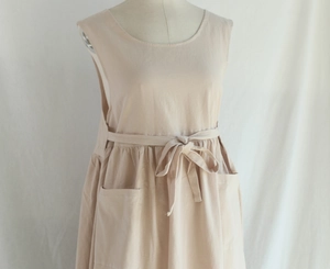 Detail of the waist tie and large side pocket on the beige cotton oversized apron