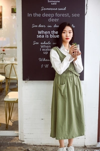 Detail of green cotton apron dress with side opening worn by florist over white shirt