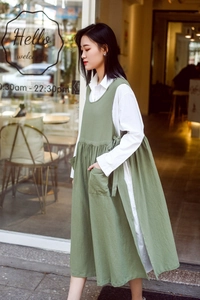 Detail of green cotton apron with side pockets and ties worn over a white shirt