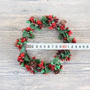 Mini Christmas wreath with red green berries and pinecones on wood background, 11cm diameter
