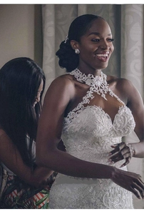 Dettaglio dell'abito da sposa in pizzo bianco con scollo all'americana e perline