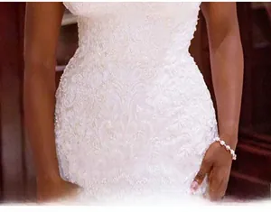 Dettaglio dell'abito da sposa a sirena bianco con pizzo floreale e ricamo in vita raffinato