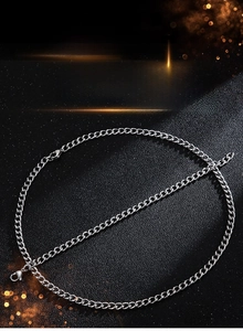Flat lay of stainless steel curb chain set with lobster clasp on a dark surface