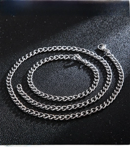 Macro shot of silver stainless steel Cuban link necklace and bracelet set on black background