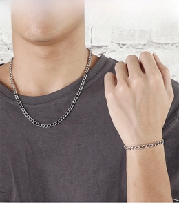 Close-up of silver stainless steel curb chain necklace and bracelet set on a model
