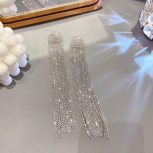 Detail view of silver long fringe tassel earrings with shimmering crystals on textured background