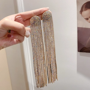 Detail of long gold tassel earrings with full diamond pavé for evening party wear