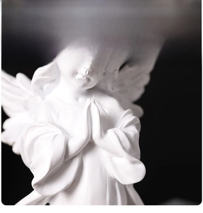 Detailed view of white resin praying angel sculpture with intricate wing textures