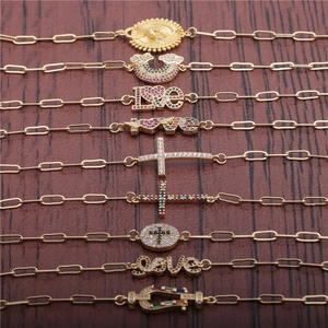 Rainbow cubic zirconia gold paperclip link bracelets with various charms on wood background