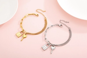 Detail of layered gold and silver chain bracelets with lock and key pendants
