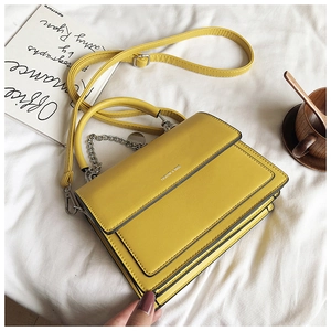 Detail of yellow flap handbag with silver chain strap and fashion logo on leather texture