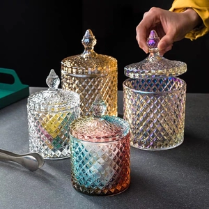 Detailed view of four colorful embossed glass jars with pointed lids on a dark table