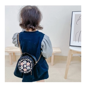 Rear view of a girl wearing a black tweed round flower bag with golden chain strap